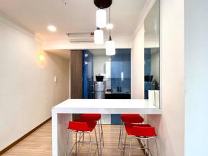 a kitchen with a white counter and red stools at Concept Suite 05 @ The Wave Residence in Tranquerah