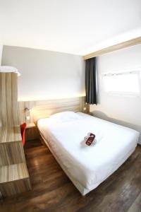 een slaapkamer met een wit bed en een raam bij Best Hotel Bordeaux Sud in Villenave-dʼOrnon