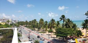 a city street with palm trees and the ocean at Flat beira mar do Cabo Branco in João Pessoa