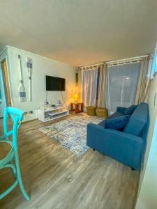 een woonkamer met een blauwe bank en een tv bij Hermoso y acogedor departamento a un paso de todo! in Papudo