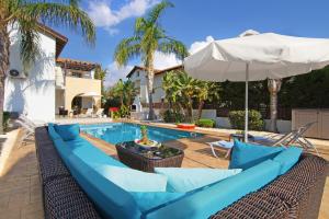 - une piscine avec un canapé bleu et un parasol dans l'établissement Villa Regina, à Ayia Napa