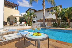 a table with glasses of wine and fruit next to a swimming pool at Villa Regina in Ayia Napa