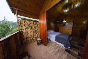 カンポス・ド・ジョルドンにあるCabanas Capivari Lodgeの木造キャビン内のベッド1台が備わるベッドルーム1室を利用します。