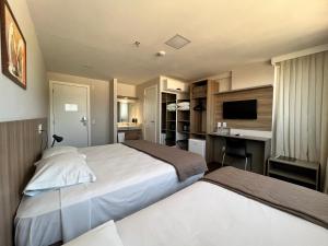 a hotel room with two beds and a desk at Hotel 7 Itajaí in Itajaí