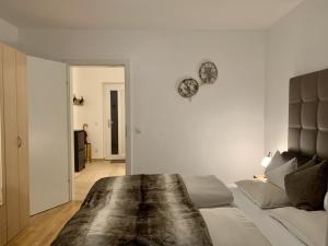 a white bedroom with a bed and a clock on the wall at Almlodge Flachau in Flachau