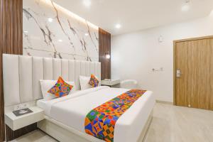 a bedroom with a white bed with a colorful blanket at FabHotel Impact in Lucknow