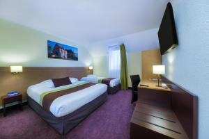 a hotel room with two beds and a flat screen tv at The Originals City, Hôtel Acadine, Le Neubourg (Inter-Hotel) in Le Neubourg