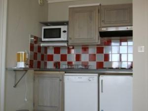 a kitchen with a red and white tiled wall at Chaleureux 2P, balcon, proche pistes & commerces - FR-1-557-99 in Les Adrets