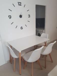 a white table with chairs and a clock on the wall at Apartamento completo en Cadaqués in Cadaqués +5 photos