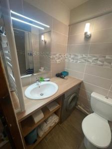 een badkamer met een wastafel, een toilet en een spiegel bij Residence Cybele "Grand Confort" in Brides-les-Bains