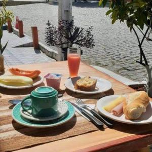a wooden table with plates of food and a drink at Pousada Berimbau in Arraial d'Ajuda