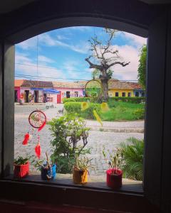 a window with potted plants in front of a building at Pousada Berimbau in Arraial d'Ajuda