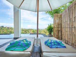 two beds on a patio with an umbrella at Villa Mimpi Tamarind in Amed