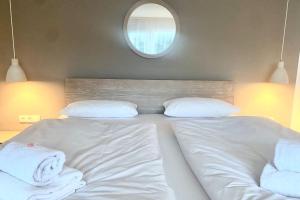 a bed with white sheets and pillows and a mirror at Ferienwohnung Bergzauber mit Balkon & Bergblick in Schliersee