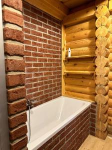 uma casa de banho com uma banheira numa parede de tijolos em Luxusní srub na Lipně em Lipno nad Vltavou
