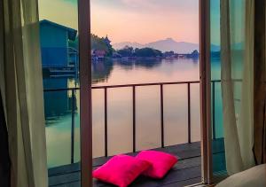 a view of the water from a window with pink pillows at Tara Raft in Kanchanaburi