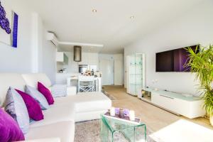 ein Wohnzimmer mit einer weißen Couch und lila Kissen in der Unterkunft Ideal Property Mallorca - Blue Palm Beach in Alcúdia