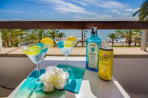 einen Tisch mit zwei Martinigläsern und einer Flasche Alkohol in der Unterkunft Ideal Property Mallorca - Blue Palm Beach in Alcúdia