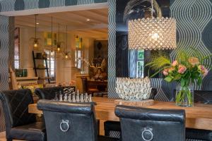una sala da pranzo con tavolo, sedie e lampadario pendente di Boutique Hotel Slenaker Vallei - Buitengewoongenieten a Slenaken