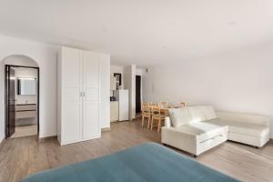 een witte woonkamer met een bank en een tafel bij ALTIDO Cosy studio wtih parking and garden 