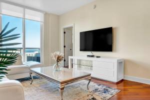 Una sala de estar con televisión y una mesa de café. en Lux 2BR Condo in Ocean Reserve with Pools and Tennis Courts, en Miami Beach