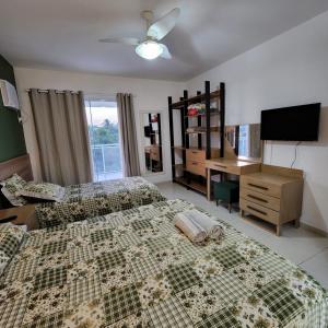 um quarto com uma cama, uma secretária e uma televisão em Casa confortável pertinho da praia com garagem e quintal em Rio das Ostras