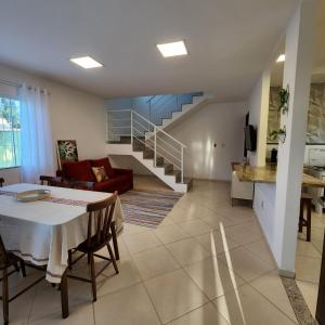 a living room with a table and a staircase at Casa confortável pertinho da praia com garagem e quintal in Rio das Ostras