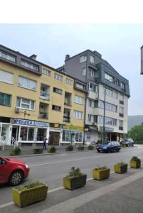 un bâtiment avec des voitures garées en face d'une rue dans l'établissement Trosoban apartman Sarajevo, Ilidza centar, à Sarajevo