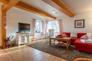 ein Wohnzimmer mit einem roten Sofa und einem TV in der Unterkunft Fischerhütte in Westerhever