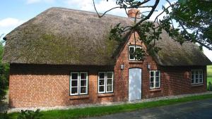 a red brick house with a thatched roof at Fischerhütte in Westerhever