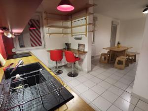 cocina con tendedero de platos y sillas rojas en T2 Parc & Cité Internationale en Caluire-et-Cuire