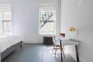 Habitación blanca con escritorio, cama y ventanas en E10-2 Designer East Village Townhouse 1BR W D en Nueva York