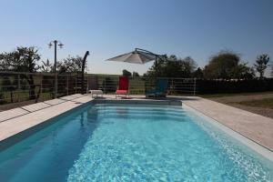 einen Pool mit 2 Stühlen und einem Sonnenschirm in der Unterkunft Roulotte La Comtoise 