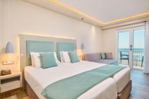 a bedroom with a large bed and a balcony at Tsilivi Beach Hotel Zakynthos in Tsilivi