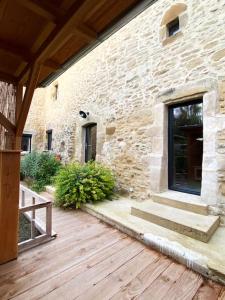 un edificio de piedra con terraza de madera y puerta en Gîte : La vieille bâtisse., en La Baume-Cornillane