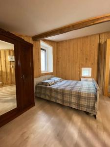 een slaapkamer met een bed in een kamer met houten wanden bij Gîte : La vieille bâtisse. in La Baume-Cornillane