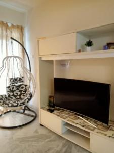 uma sala de estar com uma cadeira e uma grande televisão em D'Mentari - Cozy 3 Rooms Apartment em Porto Dickson