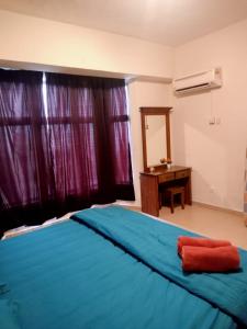 um quarto com uma cama azul e uma secretária em D'Mentari - Cozy 3 Rooms Apartment em Porto Dickson