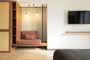 una camera da letto con una sedia rosa e una TV di Hotel Orangine a Hospitalet de Llobregat