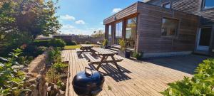 une terrasse en bois avec deux tables de pique-nique et un pot dans l'établissement Gîtes Neige d'écume, à Lampaul