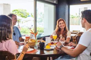 een groep mensen die rond een tafel in een restaurant zitten bij Hotel Ponta Verde Maceió in Maceió