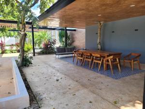 een patio met een houten tafel en stoelen bij Habitación en Iker's House in Mérida