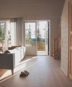 - un salon avec un canapé blanc et une porte coulissante en verre dans l'établissement Tännäskröket, à Tännäs