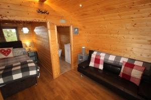 a living room with a couch and a bed in a log cabin at Carrock Pod, Hayton in Brampton