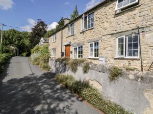 a stone house with a road in front of it at Beech Cottage in Stroud