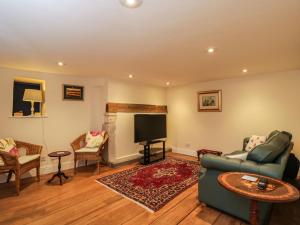 a living room with a couch and a flat screen tv at Beech Cottage in Stroud