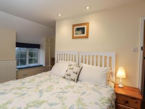 a bedroom with a bed and a lamp and a window at Beech Cottage in Stroud