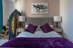 una camera da letto con un letto con lenzuola viola e due lampade di Beachfront Bolthole with Luxury, Style and Spectacular Sea Views a Herne Bay