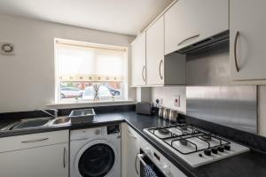 a kitchen with a stove and a washing machine at Durham Gate View in Spennymoor