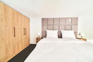 a bedroom with a large white bed and wooden cabinets at Na Fursie Apartments & Rooms in Nowy Targ